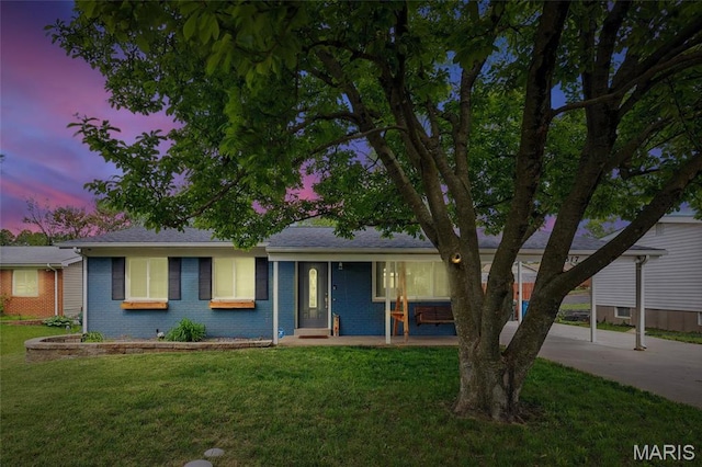 ranch-style home with driveway, a front yard, brick siding, covered porch, and a carport
