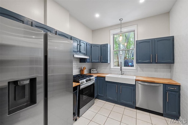 2005 Arsenal St, Saint Louis, MO 63118 - kitchen with stainless steel appliances, wood counters, a sink, under cabinet range hood, and blue cabinetry
