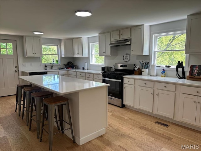 17260 Carver Dr, New London, MO 63459 - kitchen featuring gas stove, under cabinet range hood, a breakfast bar, and light wood-style floors