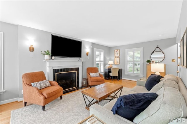 living room with a fireplace, light wood finished floors, and baseboards