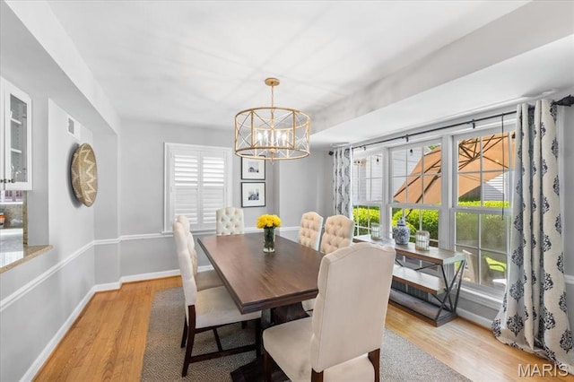 dining space with a chandelier, light wood-style flooring, healthy amount of natural light, and baseboards