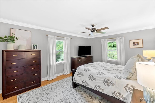 bedroom with multiple windows, light wood finished floors, ornamental molding, baseboards, and ceiling fan