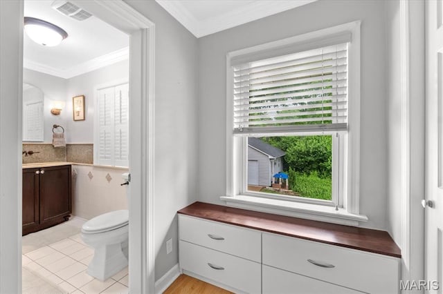 half bathroom featuring toilet, crown molding, vanity, and tile patterned flooring