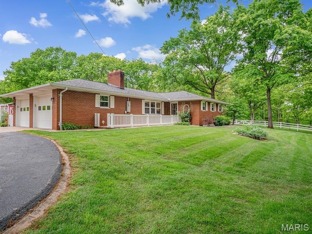 rear view of property featuring brick siding, a garage, a chimney, and driveway