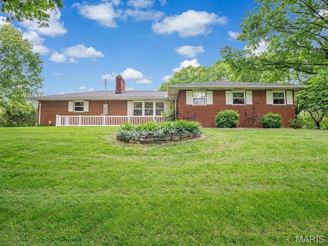 rear view of property featuring brick siding, a chimney, and a lawn