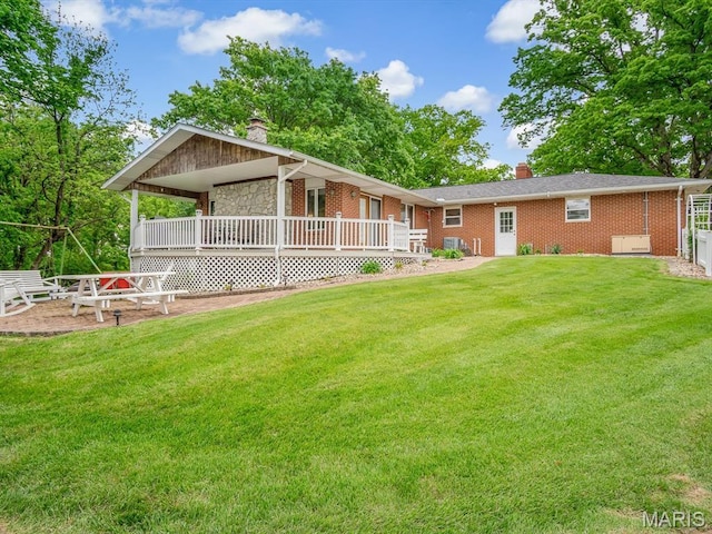 back of property featuring a chimney, a lawn, and brick siding