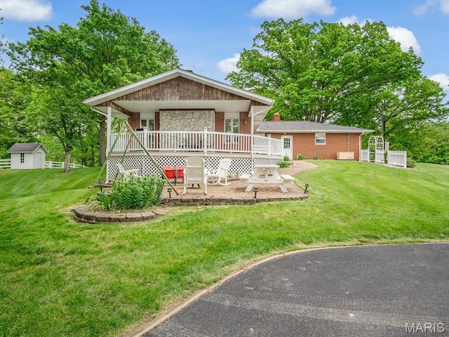 view of front facade featuring a patio area, brick siding, a front yard, and a wooden deck