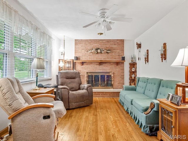 living area with light wood finished floors, ceiling fan, and a fireplace