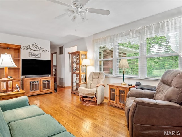 living area featuring ceiling fan, light wood-type flooring, and baseboards
