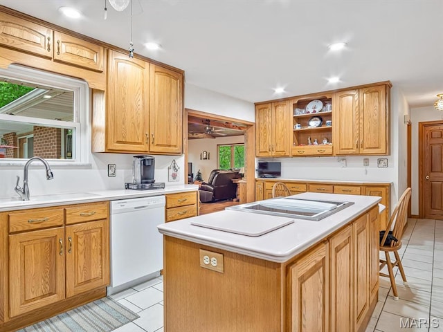 kitchen featuring white dishwasher, a sink, ceiling fan, cooktop, and a kitchen island