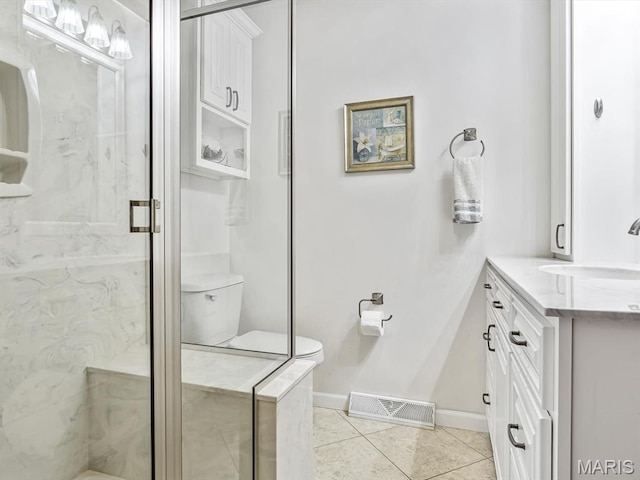 bathroom featuring toilet, tile patterned floors, vanity, a stall shower, and baseboards