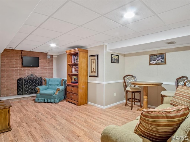 living area featuring wood finished floors, baseboards, and a paneled ceiling