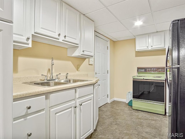 kitchen featuring electric stove, freestanding refrigerator, a sink, white cabinets, and light countertops