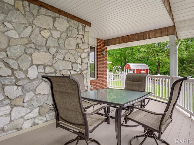 wooden deck with outdoor dining space, a shed, and an outdoor structure