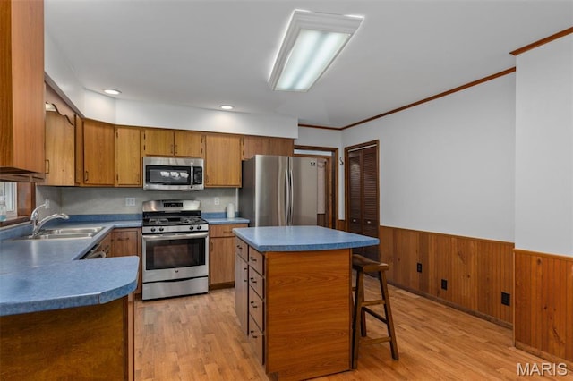 418 E Maple St, Gillespie, IL 62033 - kitchen with appliances with stainless steel finishes, a sink, brown cabinetry, wainscoting, and light wood-type flooring