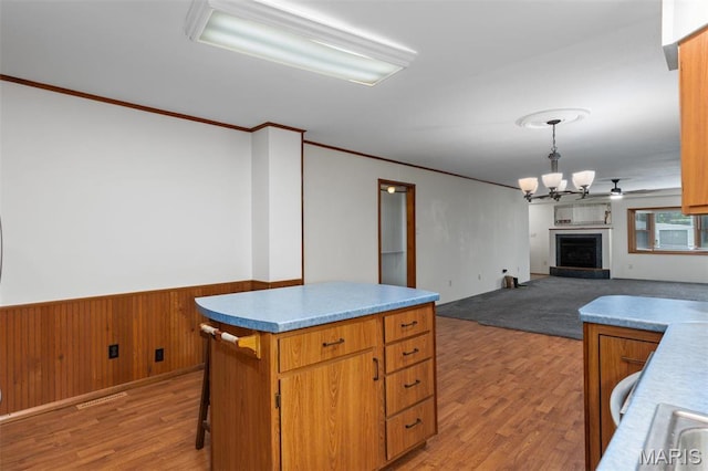 418 E Maple St, Gillespie, IL 62033 - kitchen with light wood finished floors, a wainscoted wall, a fireplace with raised hearth, a center island, and a chandelier