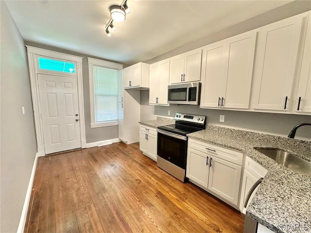 2806 Keokuk St, Saint Louis, MO 63118 - kitchen featuring appliances with stainless steel finishes, a sink, light wood-style flooring, white cabinetry, and light stone counters