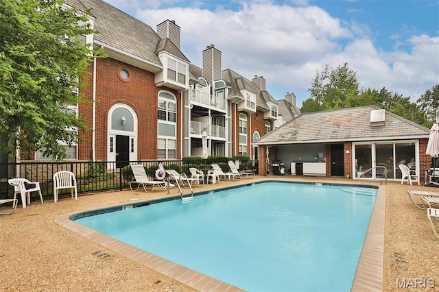 community pool featuring fence, a patio area, and a grill