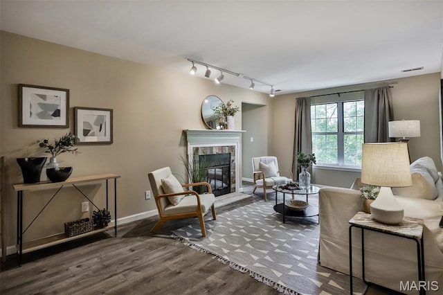 sitting room featuring track lighting, a tiled fireplace, wood finished floors, and baseboards