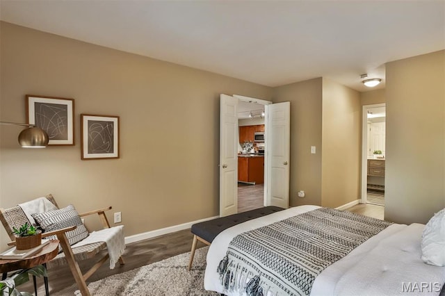 bedroom with wood finished floors, baseboards, and connected bathroom