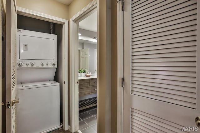 laundry area with estacked washer and dryer and tile patterned flooring