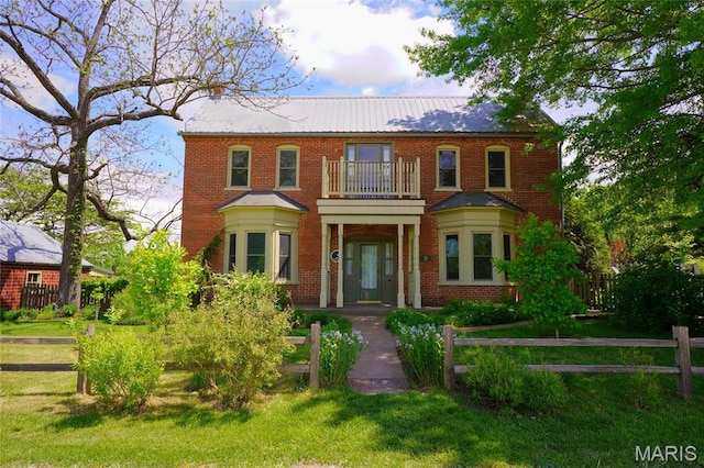 georgian-style home featuring a balcony, brick siding, and french doors