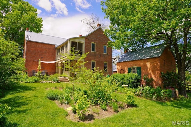 rear view of house featuring brick siding and a yard
