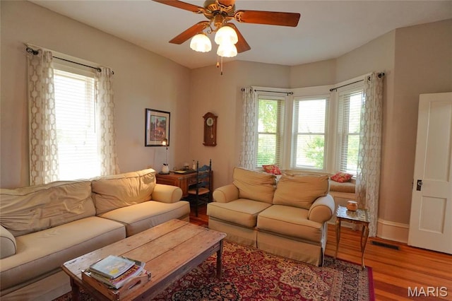 living area with wood finished floors and a ceiling fan