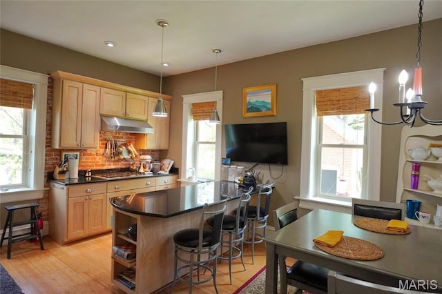 kitchen featuring dark countertops, stainless steel gas stovetop, a breakfast bar area, and light brown cabinets