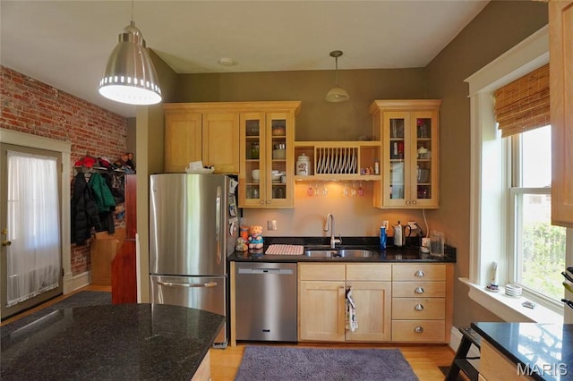 kitchen featuring a sink, appliances with stainless steel finishes, decorative light fixtures, light wood-style flooring, and brick wall