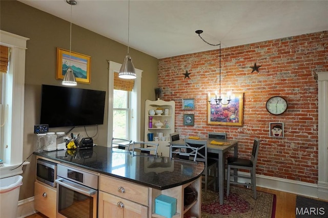 kitchen with appliances with stainless steel finishes, baseboards, brick wall, light wood-style floors, and light brown cabinets