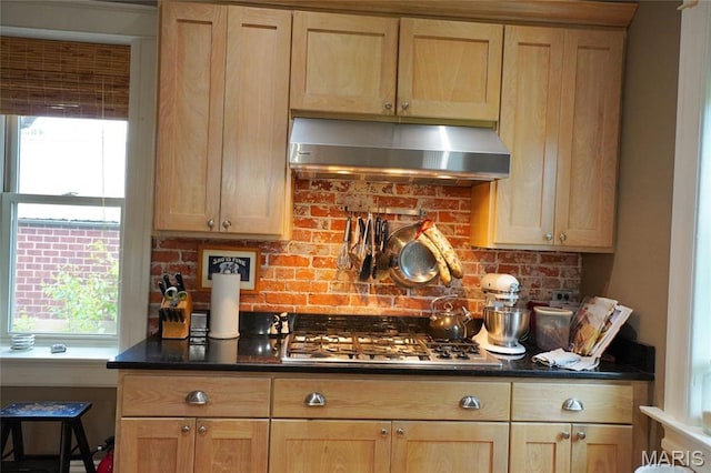 kitchen with under cabinet range hood, stainless steel gas stovetop, tasteful backsplash, and light brown cabinetry