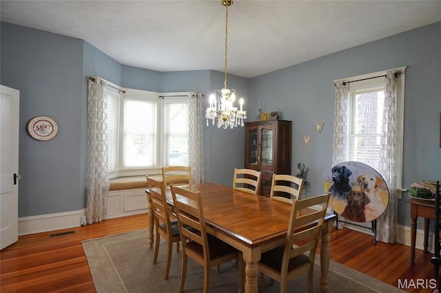 dining room with a chandelier, wood finished floors, and baseboards