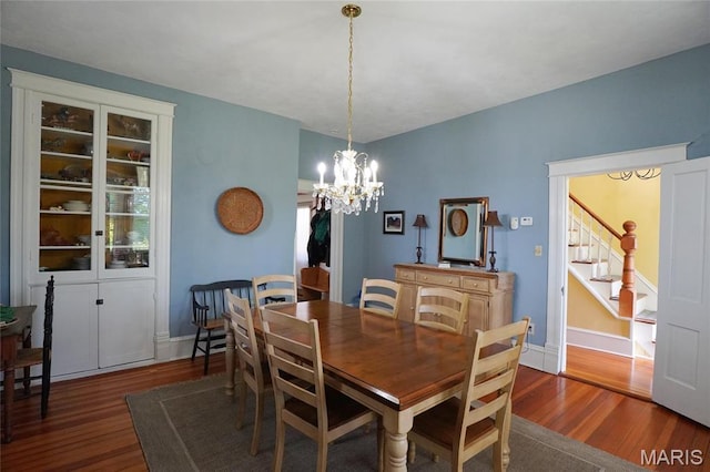 dining area with wood finished floors, a chandelier, stairway, and baseboards