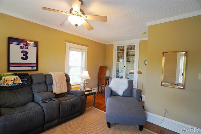 living area featuring ceiling fan, built in features, crown molding, wood finished floors, and baseboards