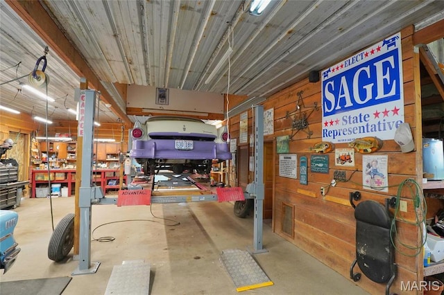 miscellaneous room featuring a workshop area, concrete flooring, a garage, and wooden walls
