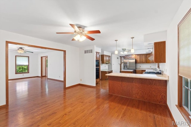 3743 Rock Creek Valley Rd, High Ridge, MO 63049 - kitchen with stainless steel fridge, brown cabinets, wood finished floors, light countertops, and a peninsula