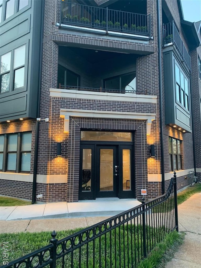 4301 Maryland Ave Unit 2, Saint Louis, MO 63108 - view of exterior entry featuring a balcony, brick siding, fence, and french doors