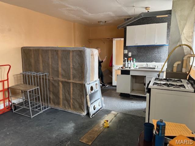 3936 Cook Ave, Saint Louis, MO 63113 - kitchen featuring concrete flooring, white cabinetry, white gas stove, and a sink