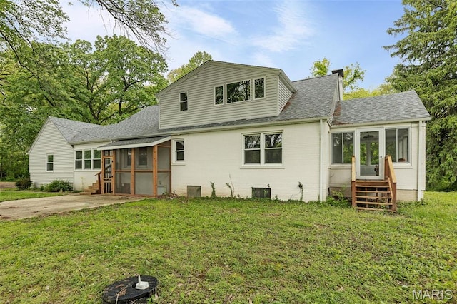 back of house featuring a sunroom, entry steps, roof with shingles, and a lawn