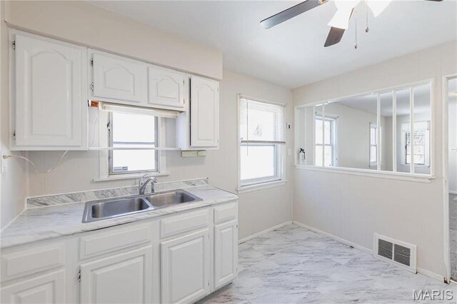 7150 Beulah Ave, Saint Louis, MO 63136 - kitchen with a sink, light marble finish flooring, white cabinets, and light countertops