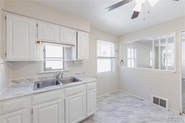 7150 Beulah Ave, Saint Louis, MO 63136 - kitchen featuring a sink, light marble finish floors, white cabinets, and light countertops