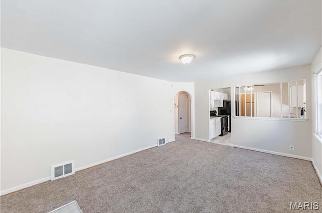 7150 Beulah Ave, Saint Louis, MO 63136 - unfurnished living room with arched walkways, light carpet, and baseboards