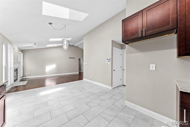 2713 Chapel View Dr, Florissant, MO 63031 - kitchen featuring a skylight, lofted ceiling, light countertops, a fireplace with flush hearth, and open floor plan