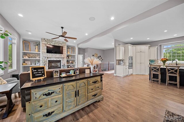 111 Foristell Ridge Ct, Foristell, MO 63348 - living room with a ceiling fan, light wood-style flooring, a stone fireplace, and recessed lighting