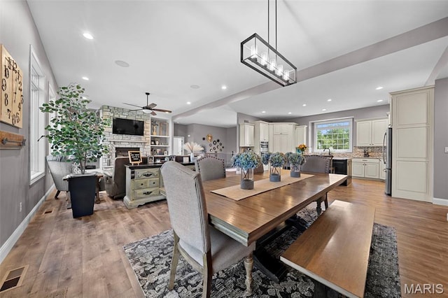 111 Foristell Ridge Ct, Foristell, MO 63348 - dining area featuring ceiling fan, a stone fireplace, light wood-style flooring, baseboards, and recessed lighting