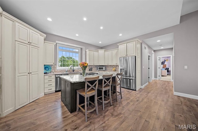 111 Foristell Ridge Ct, Foristell, MO 63348 - kitchen featuring appliances with stainless steel finishes, light wood-type flooring, a kitchen island, tasteful backsplash, and recessed lighting