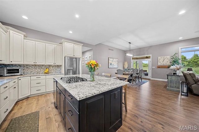 111 Foristell Ridge Ct, Foristell, MO 63348 - kitchen featuring appliances with stainless steel finishes, light wood-type flooring, a breakfast bar, a center island, and decorative backsplash