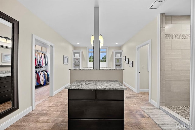 111 Foristell Ridge Ct, Foristell, MO 63348 - interior space featuring a center island, light wood-style floors, light stone counters, recessed lighting, and baseboards