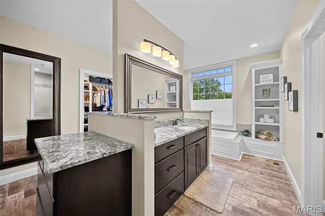 111 Foristell Ridge Ct, Foristell, MO 63348 - bathroom with wood finished floors, vanity, a bath, a walk in closet, and recessed lighting